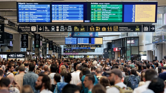 Des passagers autour des tableaux des départs et des arrivées à la gare Montparnasse à Paris, le 26 juillet 2024, alors que le réseau ferroviaire à grande vitesse français aurait été touché par des actes de malveillance perturbant le système de transport quelques heures avant la cérémonie d'ouverture des Jeux olympiques de Paris 2024.