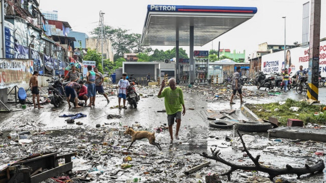 Des habitants marchent le long de débris après le passage du typhon Gaemi à Manille, le 25 juillet 2024.