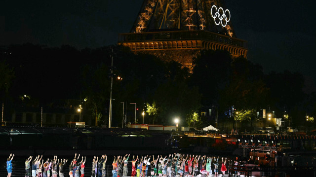 Des artistes dansent sur un bateau naviguant sur la Seine près de la Tour Eiffel lors de la cérémonie d'ouverture des Jeux Olympiques de Paris 2024 à Paris le 26 juillet 2024.