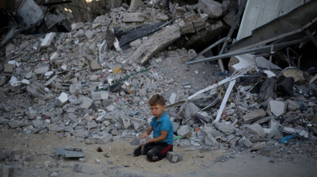 Un garçon palestinien joue sur le sable et les décombres d'un bâtiment détruit lors d'un précédent bombardement israélien, dans le camp de réfugiés d'al-Bureij, dans le centre de la bande de Gaza, le 28 juillet 2024.