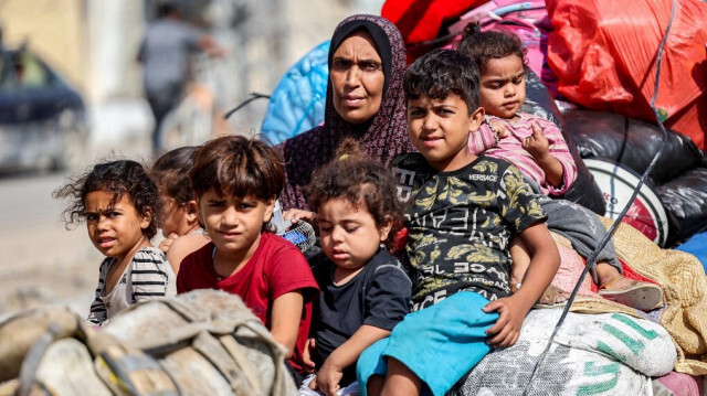 Une femme et des enfants regardant, assis avec leurs affaires sur une charrette tirée par un âne, alors qu'ils tentent de retourner chez eux dans le district de Tuffah, à l'est de la ville de Gaza, le 8 juillet 2024, dans le cadre du conflit en cours dans le territoire palestinien entre Israël et le Hamas.