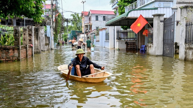 Un homme ramant sur un bateau à travers les eaux de crue dans le village de Ben Voi, à la périphérie de Hanoi, le 28 juillet 2024.