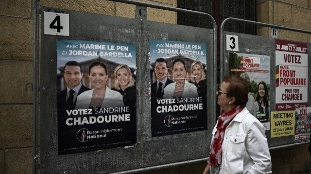 Une femme devant les affiches électorales de Sandrine Chadournec, candidate d'extrême droite du Rassemblement national (RN), à Libourne, dans le sud-ouest de la France, le 2 juillet 2024, dans le cadre des élections législatives françaises. 