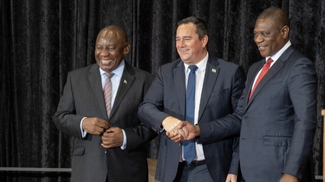 Le président sud-africain Cyril Ramaphosa (G) sourit tandis que le ministre sud-africain de l'Agriculture John Steenhuisen (C) serre la main du vice-président sud-africain Paul Mashatile (D) lors de la séance du Parlement sud-africain pour la prestation de serment des ministres, le 3 juillet 2024, au Cap. Le nouveau gouvernement d'unité de l'Afrique du Sud, dirigé par le président Cyril Ramaphosa, a prêté serment mercredi. Il s'agit du premier gouvernement de ce type dans le pays après 30 ans de règne de l'ANC. 