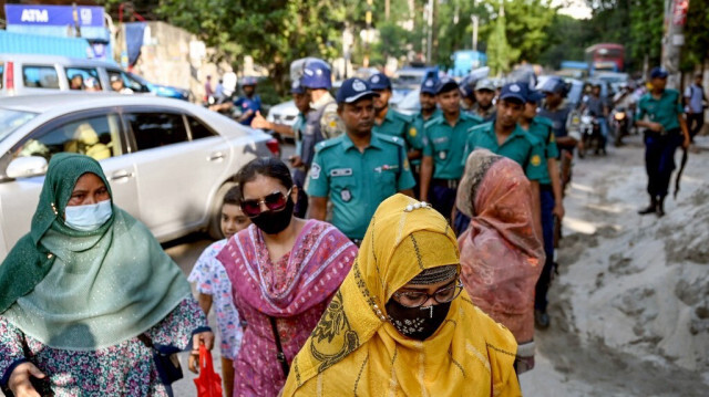 Des policiers guident Momotaz Nahar (à gauche), la mère de Nahid Islam, leader du mouvement de réforme des quotas au Bangladesh et chef du groupe Students Against Discrimination, alors qu'elle arrive au bureau de la Detective Branch de la police bangladaise, où Nahid est détenu, à Dhaka le 28 juillet 2024.