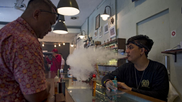 Un employé d'un café d'e-cigarettes (à droite) en train de vaper à côté d'un client à Jakarta.