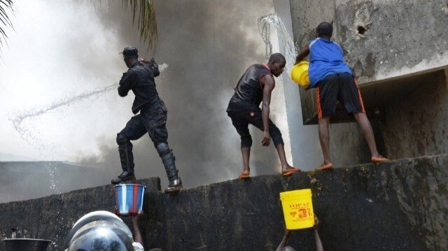 Des pompiers guinéens et des résidents d'un quartier s'efforcent d'éteindre un incendie dans une maison à Conakry, le 21 mars 2020.