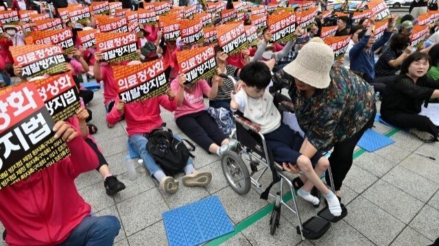 Park Ha-eun (en fauteuil roulant), une patiente sud-coréenne de 23 ans atteinte du syndrome de Cornelia de Lange, et sa mère Kim Jeong-ae (à droite) participent à un rassemblement contre la grève des médecins à Séoul, le 4 juillet 2024.