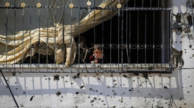 Un enfant palestinien désemparé, au balcon d'un appartement gravement endommagé par les bombardements israéliens, alors que les habitants retournent dans la ville de Khan Younes, dans le sud de la bande de Gaza, le 30 juin 2024.