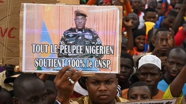 Un partisan du Conseil national de sauvegarde de la patrie (CNSP) du Niger tient une pancarte du nouveau chef militaire du Niger, le général Abdourahamane Tiani, alors qu'ils se rassemblent sur la place de la Concertation à Niamey le 20 août 2023.