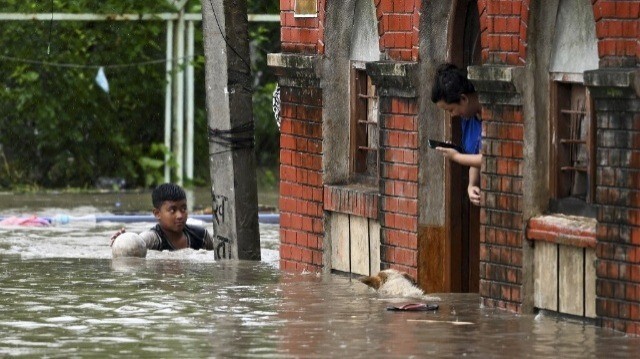 Un garçon patauge dans une rue inondée à Katmandou le 8 août 2023, après le débordement de la rivière Bagmati suite aux fortes pluies de mousson.