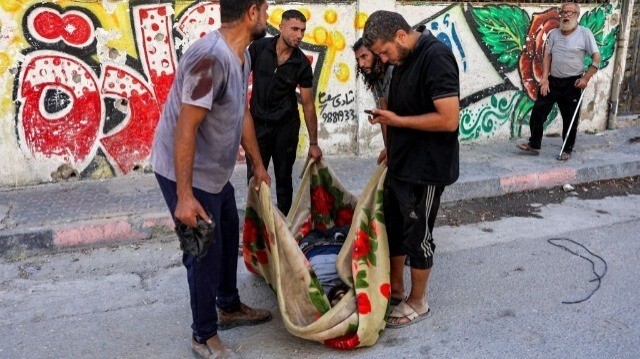 Des hommes transportent dans une couverture le corps d'une victime décédée trouvée dans le quartier de Tuffah à l'est de la ville de Gaza, le 8 juillet 2024.