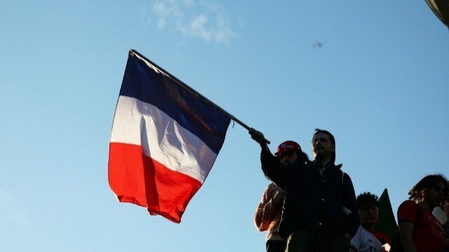 Un manifestant brandit un drapeau national français lors d'un rassemblement pour la soirée électorale suivant les résultats du second tour des élections législatives françaises sur la place de la République à Paris, le 7 juillet 2024.