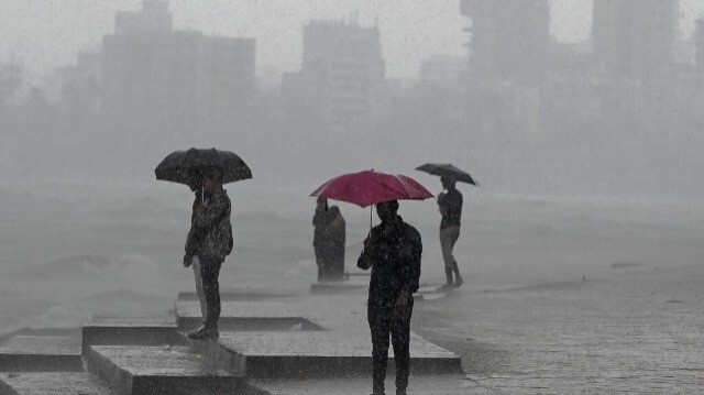 Des personnes profitent des averses de pluie près du front de mer à Mumbai le 8 juillet 2024.