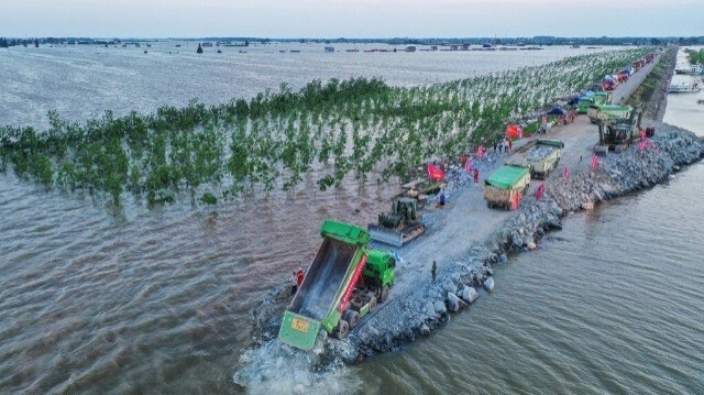 Cette photo prise le 7 juillet 2024 montre une vue aérienne d'ouvriers réparant une brèche sur une digue du lac Dongting dans le comté de Huarong, dans la province centrale du Hunan en Chine.