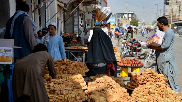 Une femme afghane vêtue d'une burqa achète des biscuits locaux appelés "kulcha" sur un marché de Kandahar le 15 juin 2024, à la veille de la fête musulmane de l'Aïd al-Adha.