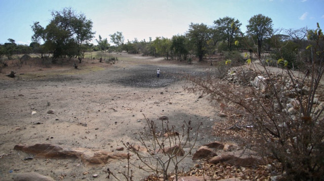 Le 2 juillet 2024, l'agriculteur Takesure Chimbu marche sur le lit asséché du barrage de Kapotesa à Mudzi, qui s'est complètement asséché en raison de la sécheresse induite par le phénomène El Niño. 