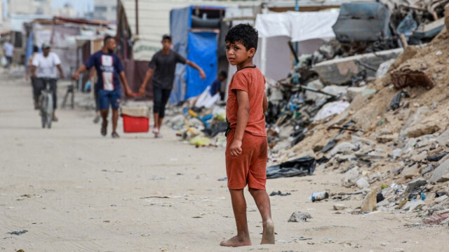 Un enfant palestinien attristé profondément, marche les pieds nus dans une rue criblée de déchets et de décombres en raison des bombardements de l'armée d'occupation israélienne, à Khan Younes, dans le sud de la bande de Gaza, en Palestine, le 6 juillet 2024.