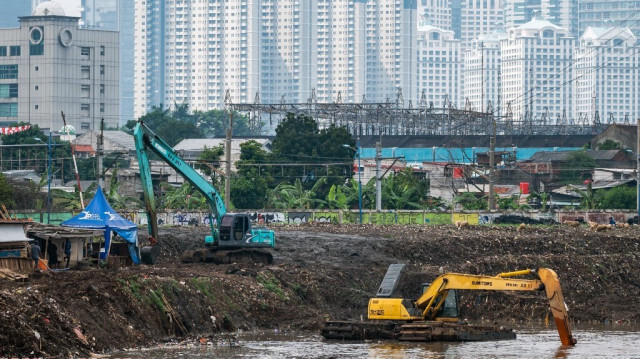 Des excavateurs enlèvent le limon et les débris de la rivière Ciliwung dans le cadre de mesures d'atténuation des inondations à Jakarta, le 9 juillet 2024.