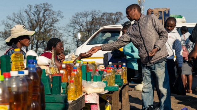 Un client achète de l'huile de cuisson à un stand où des mesures d'huile de cuisson plus petites que la norme sont vendues sur le marché de Harare Mbare Musika, le 15 juillet 2019.
