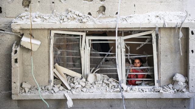 Une petite fille palestinienne désemparée, regarde par la fenêtre d'une maison endommagée lors des bombardements de l'armée d'occupation israélienne sur le camp de réfugiés de Nuseirat, dans le centre de la bande de Gaza, en Palestine, le 6 juillet 2024.