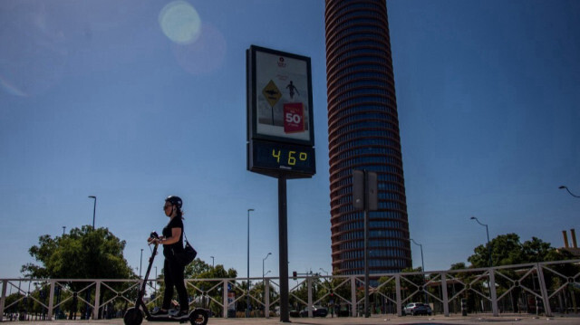 Une femme conduit une trottinette devant un thermomètre indiquant 46 degrés Celsius, dans une rue de Séville, le 23 juillet 2024. 