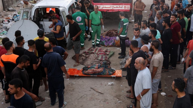 Des Palestiniens regardent les premiers secours transporter les corps des personnes tuées lors d'une frappe israélienne sur une école de Gaza City le 10 août 2024, qui a fait plus de 100 morts.