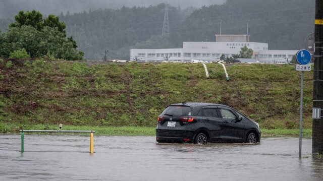 Une voiture avance sur une route inondée à la suite du typhon numéro 5, désormais classé comme tempête tropicale Maria, à Kuji, préfecture d'Iwate, le 12 août 2024.






