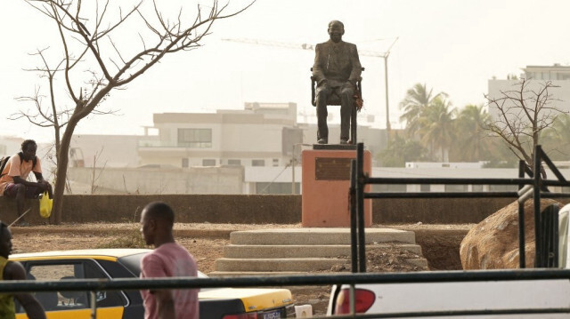 Des banlieusards passent devant la statue de l'ancien président sénégalais Léopold Sedar Senghor à Dakar, le 15 avril 2024. 