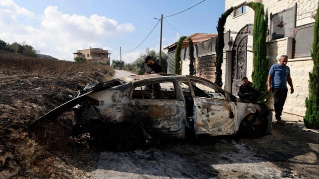 Des Palestiniens inspectent une voiture incendiée après une attaque de colons juifs contre le village de Jit, près de Naplouse, en Palestine occupée, le 16 août 2024.