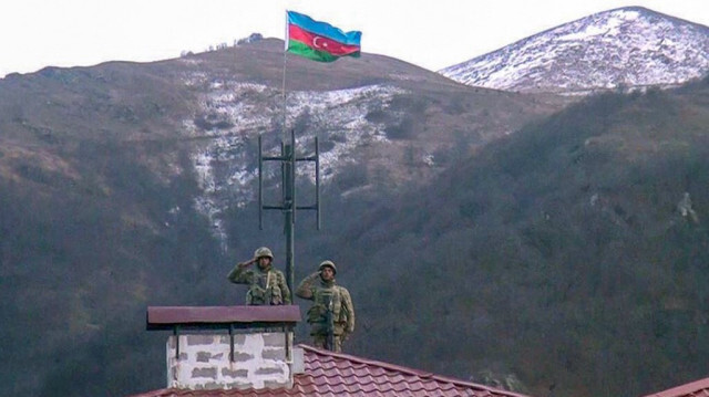 Des soldats azerbaïdjanais saluant alors qu'ils attachent un drapeau sur le toit d'un bâtiment dans la ville de Kalbajar, au Nagorno-Karabakh, le 28 novembre 2020. 