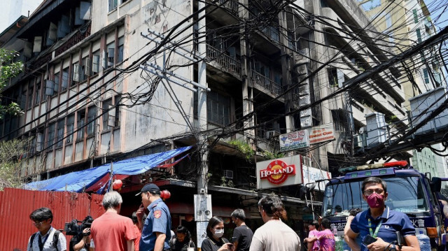 Des personnes, des policiers et des journalistes se trouvent sur les lieux de l'incendie qui a ravagé un immeuble dans le quartier chinois de Manille, le 2 août 2024.