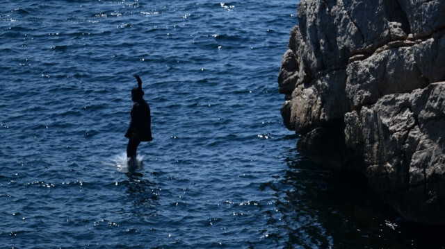 Une femme portant un burkini plonge dans la mer pour se rafraîchir dans le quartier des Goudes à Marseille, le 21 août 2023. 