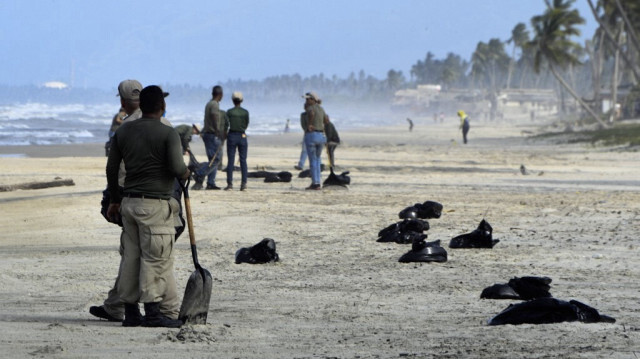 Des membres de l'Institut des parcs nationaux (INPARQUES) ramassent des résidus de pétrole sur la plage de Boca de Yaracuy dans l'État de Falcon, au Venezuela, le 19 août 2024.