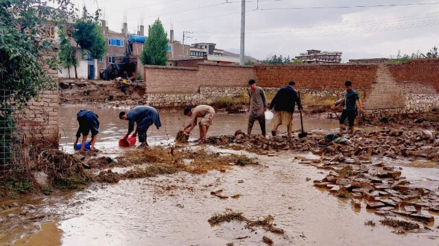 Des Afghans évacuent les eaux de crue à l'aide de pelles et de seaux, après de fortes pluies dans la banlieue de Kaboul, le 20 août 2024.