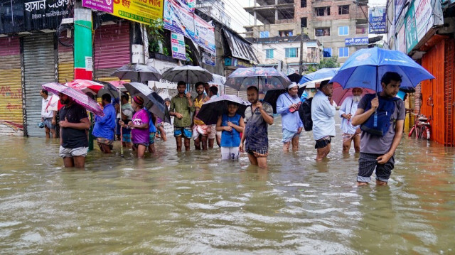 Des personnes portant des parapluies pataugent dans une rue inondée par la pluie à Feni, le 22 août 2024.