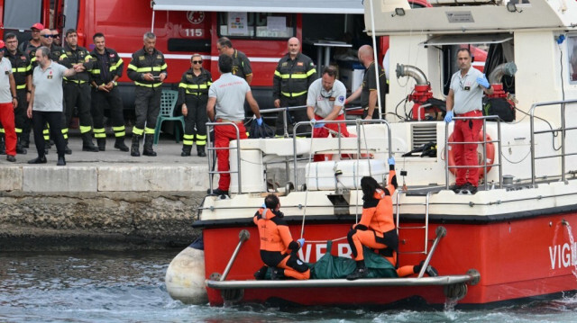 Les plongeurs des Vigili del Fuoco, le Corps des pompiers italiens, arrivent avec un sac mortuaire à l'arrière du bateau à Porticello, près de Palerme, le 21 août 2024, deux jours après le naufrage du yacht de luxe battant pavillon britannique, le Bayesian.