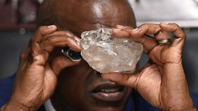 Le président du Botswana, Mokgweetsi Masisi, regarde un gros diamant découvert au Botswana dans son bureau de Gaborone, le 22 août 2024. 