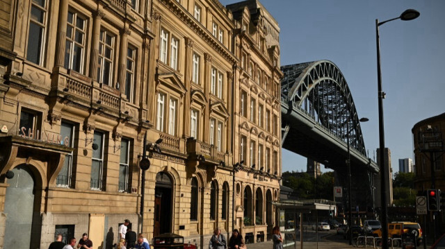 Des personnes mangent à l'extérieur de la Uno's Trattoria sous le soleil du début de soirée, près du Tyne Bridge à Newcastle upon Tyne, dans le nord-est de l'Angleterre, le 17 septembre 2020.