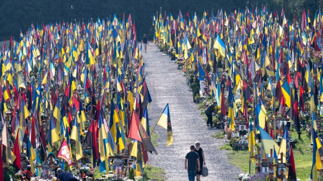 Des personnes marchent parmi les tombes du cimetière du Champ de Mars à Lviv, le 24 août 2024, pour commémorer les soldats tombés au combat à l'occasion de la fête de l'indépendance de l'Ukraine, dans le contexte de l'invasion de l'Ukraine par la Russie.