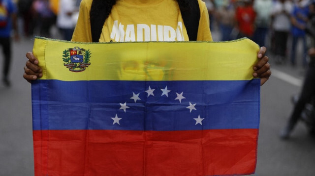 Une partisane du président Nicolas Maduro tient un drapeau national alors qu'elle participe à une marche pour défendre la loi contre le fascisme, le néofascisme et les expressions similaires à Caracas, le 23 août 2024. 