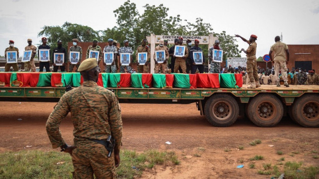 Des militaires burkinabés tiennent des portraits de soldats derrière les cercueils lors de l'enterrement des soldats tués à Gaskinde, à Ouagadougou le 8 octobre 2022.  