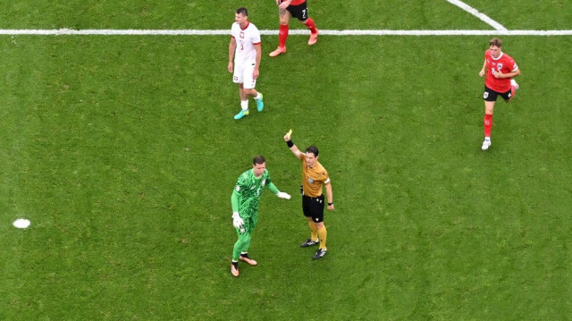 L'arbitre turc Umut Meler présente un carton jaune au gardien de but polonais #01 Wojciech Szczesny après une faute sur le milieu de terrain autrichien #09 Marcel Sabitzer (non photographié) lors du match de football du groupe D de l'UEFA Euro 2024 entre la Pologne et l'Autriche à l'Olympiastadion à Berlin le 21 juin 2024.