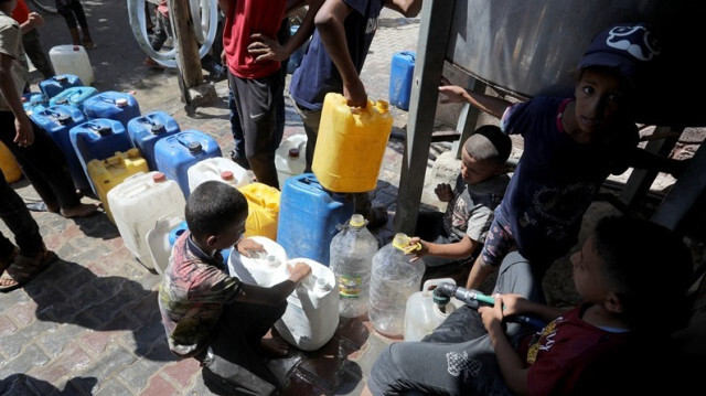 Des enfants palestiniens, font la queue pour remplir leurs bouteilles d'eau potable, distribuée par des organisations humanitaires, à Deir Al-Balah dans la Bande de Gaza.