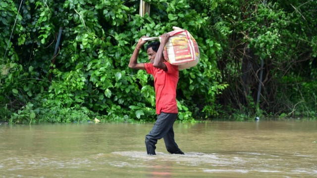 Un homme transporte ses affaires dans une rue inondée après de fortes pluies en périphérie d'Ahmedabad, le 28 août 2024. 