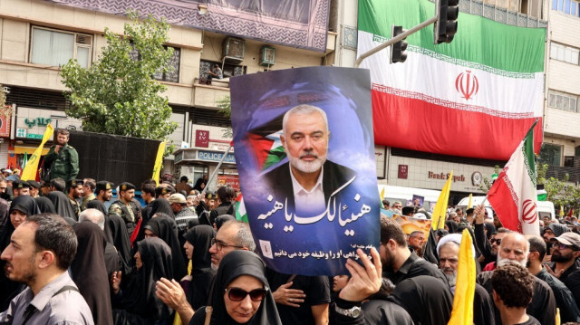 Des Iraniens tiennent des portraits du chef du Hamas, Ismail Haniyeh, lors de son cortège funèbre, à Téhéran, le 1er août 2024, avant son enterrement au Qatar.