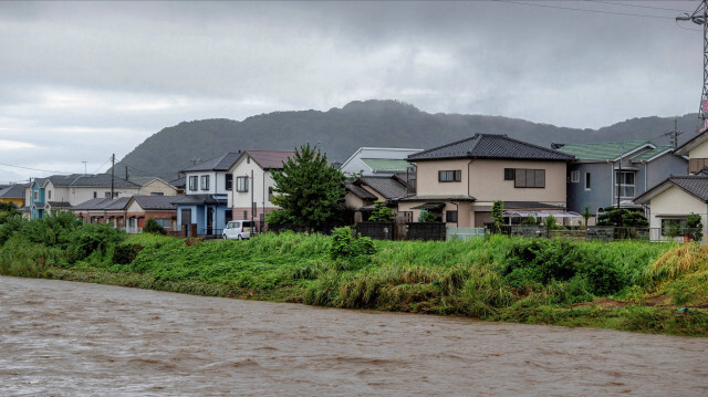 Les eaux boueuses de la rivière Kaneme s'écoulent devant les maisons alignées derrière les berges de la rivière à la suite du typhon Shanshan dans la ville de Hiratsuka, préfecture de Kanagawa, le 30 août 2024. Le typhon Shanshan s'est affaibli pour devenir une tempête tropicale le 30 août, mais il a continué à déverser des pluies torrentielles alors qu'il traversait lentement le Japon, provoquant des dégâts dans les transports et des alertes aux glissements de terrain, qui ont fait jusqu'à six morts.