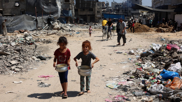 Des enfants palestiniens transportent des pots de soupe près d'un point de distribution de nourriture dans le camp de réfugiés de Jabalia, dans le nord de la bande de Gaza, le 21 août 2024, alors que le conflit entre Israël et le Hamas se poursuit dans le territoire palestinien.