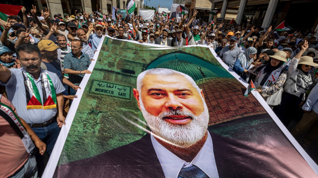 Des manifestants brandissant des pancartes et des drapeaux de la Palestine lors d'un rassemblement à Rabat le 3 août 2024, pour protester contre l'assassinat du chef du groupe militant palestinien Hamas, Ismail Haniyeh (portrait).