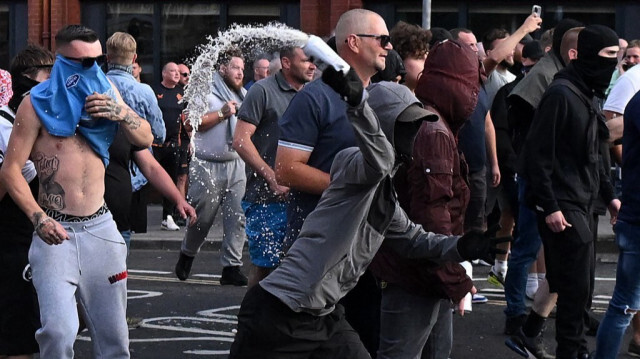 Un manifestant masqué lance une canette vers la police lors des affrontements à Bristol, au Royaume-Uni, le 3 août 2024.